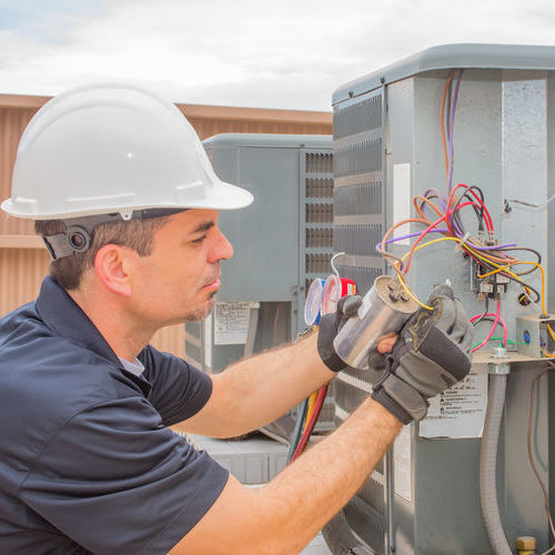 hvac technician checking capacitor on air conditioner