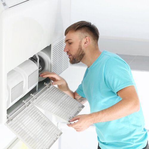 Young man investigating his air conditioning unit.