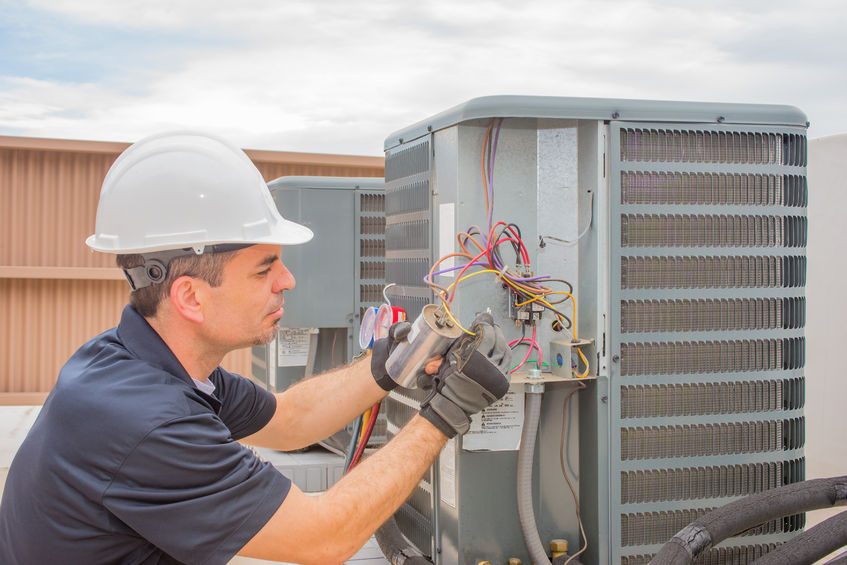 hvac technician checking capacitor on air conditioner